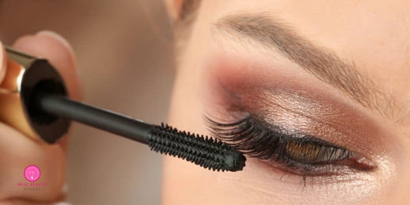 woman applying mascara on top of eyeshadow and eyeliner