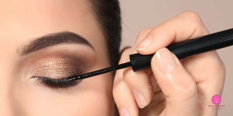 woman wearing eyeshadow first and applying eyeliner