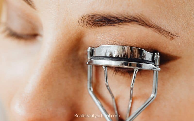 woman curling her eyelashes 