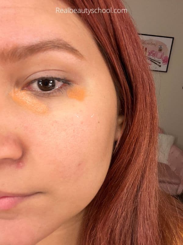 woman with dark circles under eyes wearing orange and yellow concealer