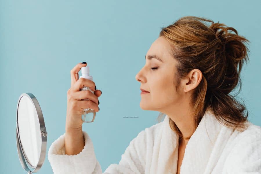 woman applying setting spray on face
